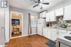 Kitchen with sink, backsplash, white appliances, white cabinets, and light wood-type flooring - 