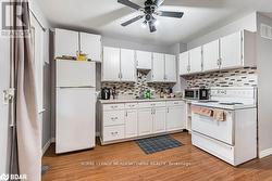 Kitchen with white appliances, white cabinetry, sink, and light wood-type flooring - 