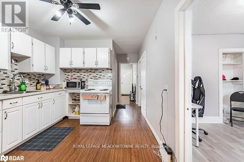 Kitchen with white cabinetry, sink, white range with electric cooktop, light wood-type flooring, and decorative backsplash - 77 Province Street N, Hamilton, ON - Indoor Photo Showing Kitchen