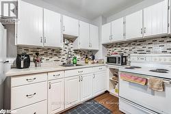 Kitchen with dark hardwood / wood-style flooring, white cabinetry, sink, and electric range - 