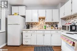 Kitchen with white cabinets, sink, and white appliances - 