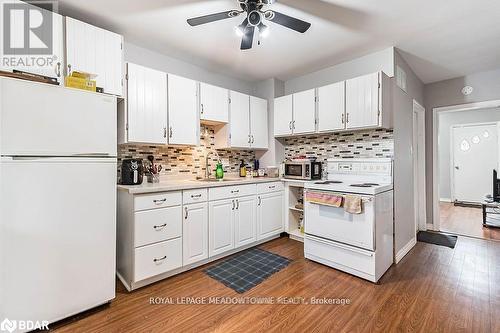 Kitchen with white appliances, white cabinetry, sink, and hardwood / wood-style flooring - 77 Province Street N, Hamilton, ON - Indoor Photo Showing Kitchen