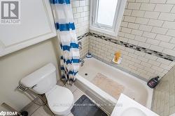 Bathroom with toilet, tile patterned flooring, and shower / bathtub combination with curtain - 