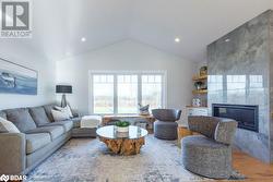 Living room featuring wood-type flooring, vaulted ceiling, and a fireplace - 