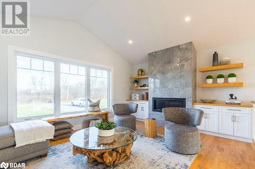 Living room featuring a fireplace, lofted ceiling, light hardwood / wood-style floors, and plenty of natural light - 1647 Lakeside Drive, Hillier, ON - Indoor