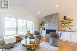 Living room featuring a fireplace, lofted ceiling, light hardwood / wood-style floors, and plenty of natural light - 