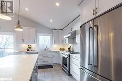 Kitchen featuring premium appliances, lofted ceiling, and white cabinets - 