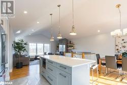 Kitchen with light hardwood / wood-style flooring, vaulted ceiling, decorative light fixtures, and a kitchen island - 