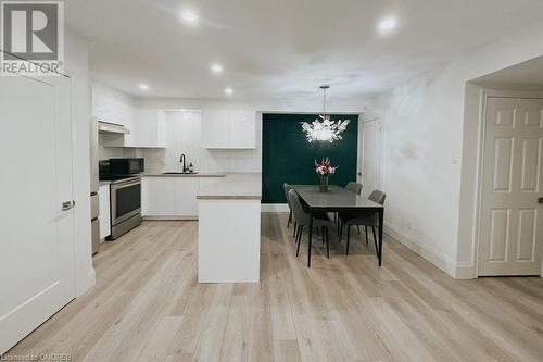 Kitchen featuring light wood-type flooring, pendant lighting, sink, stainless steel range, and white cabinets - 1701 Lampman Avenue Unit# 601, Burlington, ON - Indoor Photo Showing Other Room