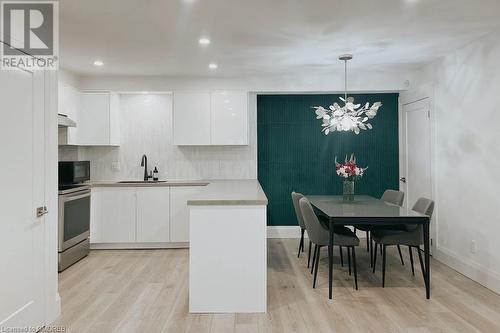 Kitchen featuring white cabinetry, hanging light fixtures, and stainless steel range oven - 1701 Lampman Avenue Unit# 601, Burlington, ON - Indoor