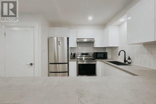 Kitchen featuring white cabinets, decorative backsplash, sink, appliances with stainless steel finishes, and range hood - 1701 Lampman Avenue Unit# 601, Burlington, ON - Indoor Photo Showing Kitchen