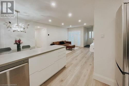 Kitchen featuring white cabinets, light wood-type flooring, pendant lighting, and stainless steel refrigerator - 1701 Lampman Avenue Unit# 601, Burlington, ON - Indoor