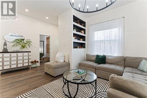 Living room featuring dark wood-type flooring, a chandelier, and built in shelves - 50 Ontario Street, Brantford, ON - Indoor Photo Showing Living Room