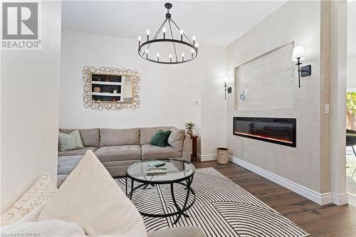 Living room featuring dark hardwood / wood-style flooring, an inviting chandelier, and a large fireplace - 50 Ontario Street, Brantford, ON - Indoor Photo Showing Living Room With Fireplace