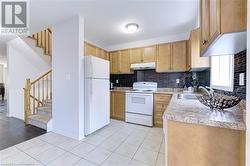 Kitchen with decorative backsplash, sink, white appliances, and light wood-type flooring - 