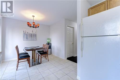 Dining space with a chandelier and light tile patterned floors - 151 Green Road S Unit# 26, Stoney Creek, ON - Indoor Photo Showing Dining Room