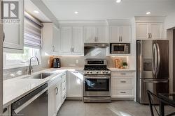 Kitchen with stainless steel appliances, light quartz counters, white cabinets, backsplash - 