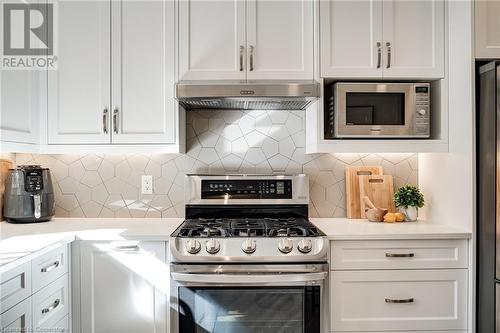 Kitchen with stainless steel appliances, light quartz counters, white cabinets, backsplash - 2301 Cavendish Drive Unit# 106, Burlington, ON - Indoor Photo Showing Kitchen