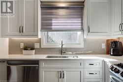 Kitchen with stainless steel appliances, light quartz counters, white cabinets, backsplash. Custom window covering - 