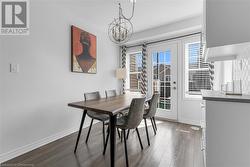 Dining area featuring dark wood-type flooring and a notable chandelier - 