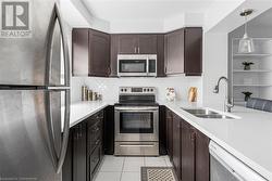 Kitchen with stainless steel appliances, light tile patterned flooring, sink, decorative light fixtures, and decorative backsplash - 