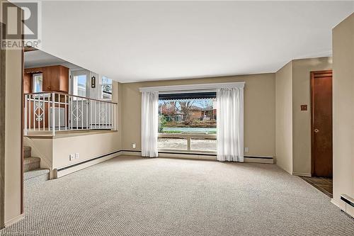 Main floor family room features large window to backyard - 16 Harvest Lane, Brantford, ON - Indoor Photo Showing Other Room