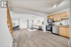 Kitchen with appliances with stainless steel finishes, light brown cabinetry, sink, ceiling fan, and light hardwood / wood-style flooring - 