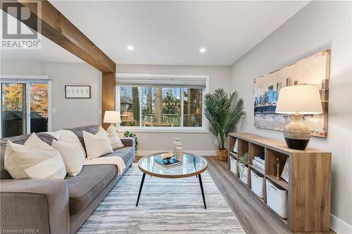 Living room with a wealth of natural light, beam ceiling, and light hardwood / wood-style flooring - 54 Pembers Pass, Woodstock, ON 