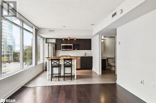 Kitchen with stainless steel appliances, a breakfast bar area, a textured ceiling, a kitchen island, and light wood-type flooring - 15 Brunel Court Unit# 201, Toronto, ON 