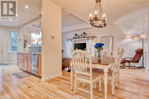 Dining space with a barn door, light hardwood / wood-style floors, sink, and a notable chandelier - 5 Twentyplace Boulevard, Mount Hope, ON 