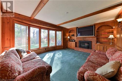 Carpeted family room with a fireplace, wooden walls, and lofted ceiling with beams - 218 Northshore Boulevard W, Burlington, ON 