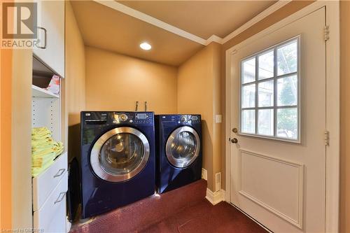 Laundry area with ornamental molding, cabinets, separate washer and dryer, door to the backyard - 218 Northshore Boulevard W, Burlington, ON 