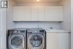 Clothes washing area with cabinets, sink, and washing machine and clothes dryer - 