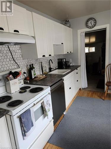 Kitchen featuring dishwashing machine, range, range hood, white cabinets, and light wood-type flooring - 765 7Th Street A E, Owen Sound, ON - Indoor Photo Showing Kitchen