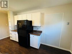 Kitchen with black refrigerator, white cabinetry, dark wood-type flooring, and backsplash - 