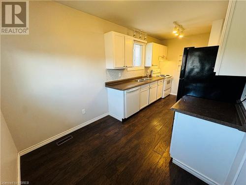 Kitchen with tasteful backsplash, white cabinetry, dark hardwood / wood-style flooring, sink, and white appliances - 49 Beaver Crescent, North Bay, ON - Indoor Photo Showing Kitchen With Double Sink