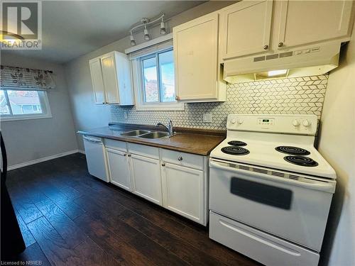 Kitchen featuring dark wood-type flooring, white appliances, white cabinets, and a healthy amount of sunlight - 49 Beaver Crescent, North Bay, ON - Indoor Photo Showing Kitchen With Double Sink