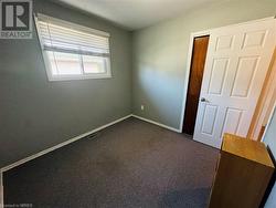 Unfurnished room featuring dark colored carpet - 