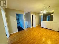 Empty room featuring light wood-type flooring and a chandelier - 