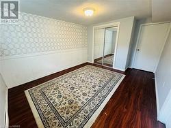 Bedroom with dark wood-type flooring, a closet, and a textured ceiling - 