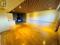 Unfurnished living room featuring a wood stove, light hardwood / wood-style floors, and wooden ceiling - 