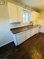 Kitchen with dark hardwood / wood-style flooring, white appliances, sink, and white cabinets - 