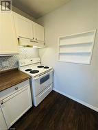 Kitchen featuring white cabinets, dark hardwood / wood-style flooring, and electric range - 