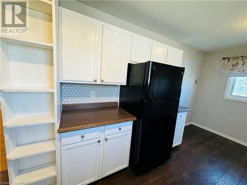 Kitchen with white cabinets, black refrigerator, dark hardwood / wood-style flooring, and tasteful backsplash - 49 Beaver Crescent, North Bay, ON - Indoor