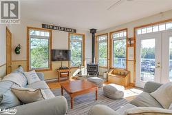 Sunroom featuring a healthy amount of sunlight, a wood stove, and a baseboard heating unit - 