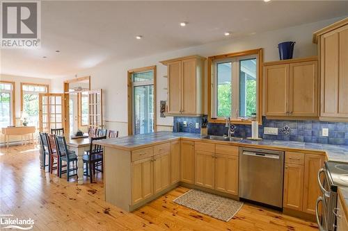 Kitchen featuring appliances with stainless steel finishes, sink, tile counters, light hardwood / wood-style floors, and kitchen peninsula - 1320 360 Island, Port Severn, ON - Indoor