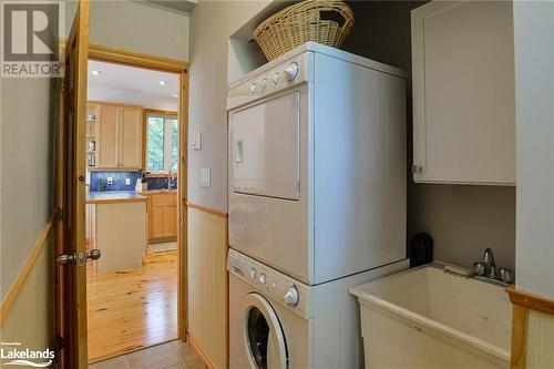 Laundry room featuring cabinets, light hardwood / wood-style flooring, sink, and stacked washer and clothes dryer - 1320 360 Island, Port Severn, ON - Indoor Photo Showing Laundry Room