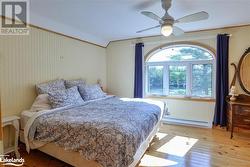 Bedroom featuring ceiling fan, baseboard heating, and light wood-type flooring - 