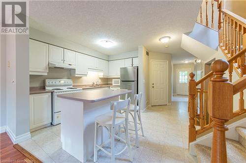 Kitchen featuring a kitchen island, white cabinets, a textured ceiling, and white electric range oven - 421 Beaver Creek Road, Waterloo, ON - Indoor Photo Showing Kitchen