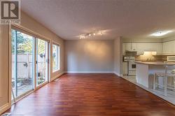 Kitchen with white cabinetry, a textured ceiling, dark hardwood / wood-style floors, sink, and white appliances - 